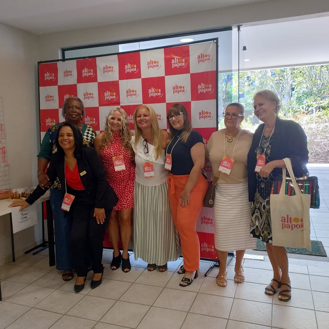 Grupo de educadoras posando diante de um painel em evento de educação