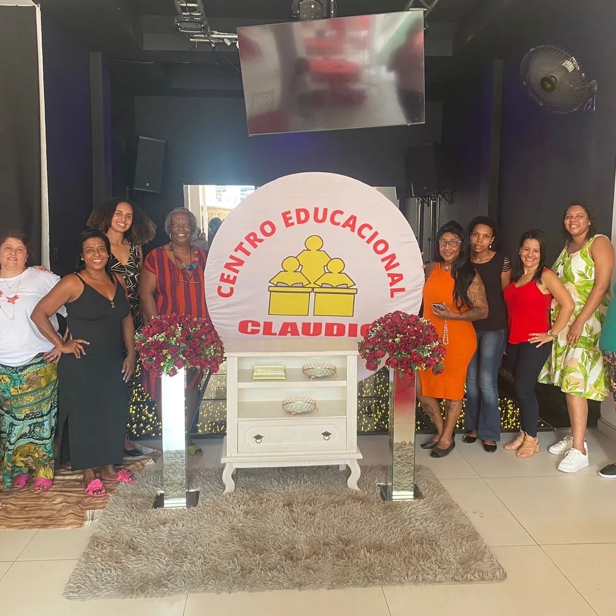 Equipe do Centro Educacional Claudio reunida ao redor de um painel com o logo da escola