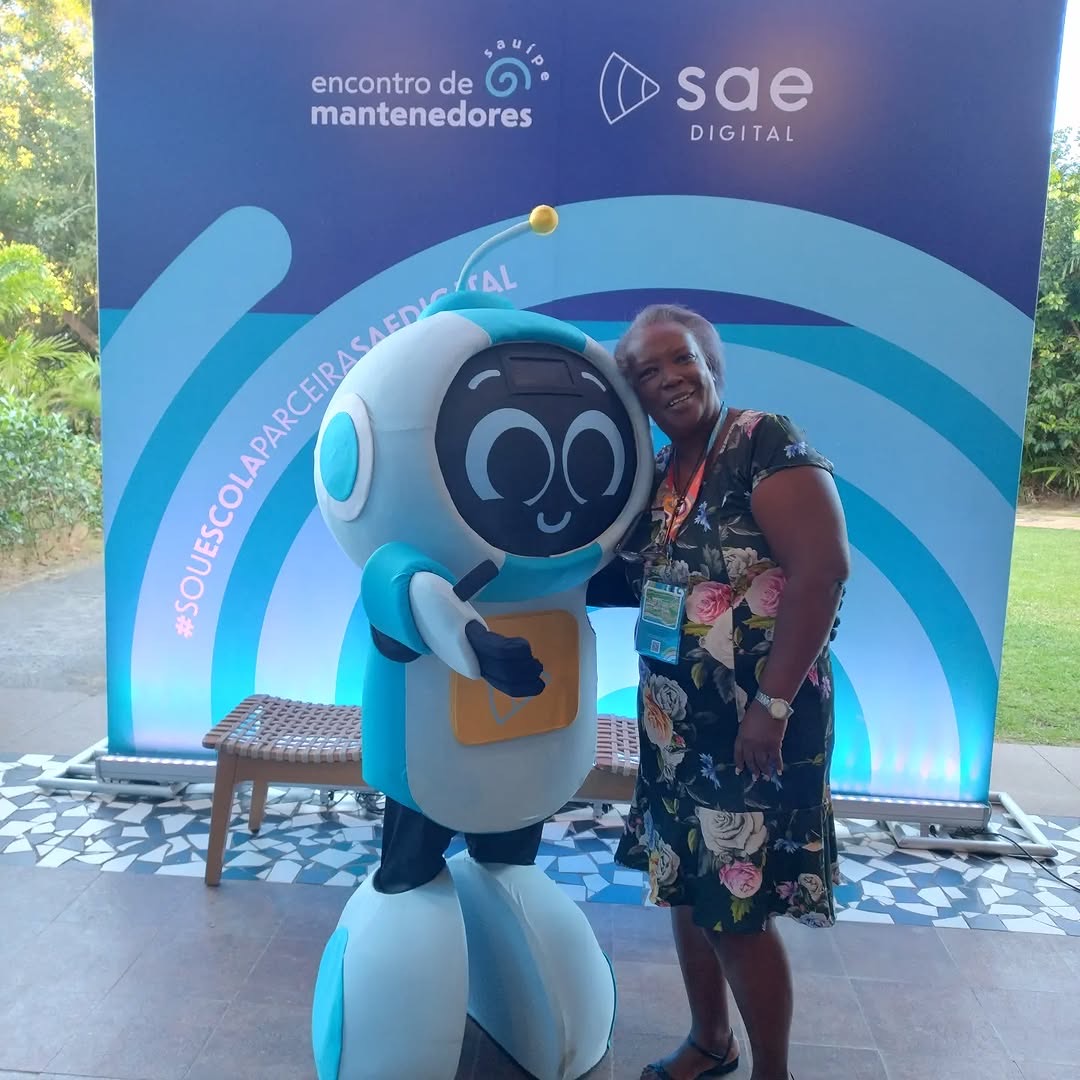 Representante do Centro Educacional Claudio ao lado do robô mascote do SAE Digital em um evento